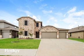 Conroe house for rent - A large house with a stone facade and a garage door.