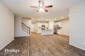 Conroe house for rent - A spacious living room with a staircase and a kitchen in the background.