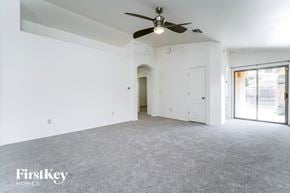 Tucson house for rent - an empty living room with a ceiling fan and white walls