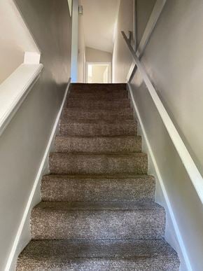 Louisville house for rent - A staircase with a carpeted runner and white handrails.