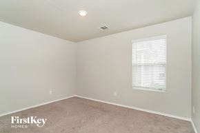San Antonio house for rent - a bedroom with a carpeted floor and a window