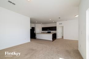 Haines City house for rent - A spacious, empty room with a kitchenette in the background.