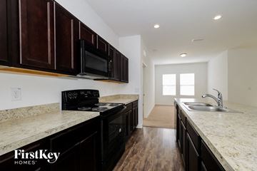 Haines City house for rent - A kitchen with dark wood cabinets and a granite countertop.