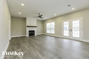 Clarksville house for rent - A spacious room with a fireplace and a ceiling fan.