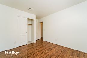 Tucson house for rent - a bedroom with white walls and wood flooring and a closet