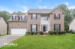 Matthews house for rent - a beige brick house with black shutters and a white garage door