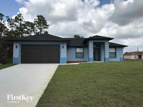 Lehigh Acres house for rent - A blue house with a black garage door is for sale.