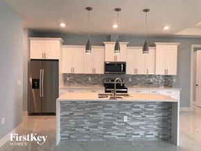 Lehigh Acres house for rent - A kitchen with a stone counter top and a refrigerator.