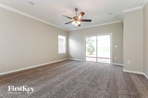 Jacksonville house for rent - A spacious room with a ceiling fan and carpeted floor.