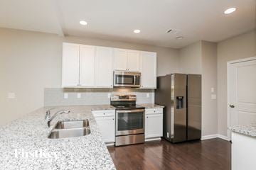 Lawrenceville house for rent - a kitchen with white cabinets and stainless steel appliances