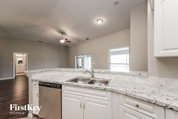 Lehigh Acres house for rent - a kitchen with white cabinets and granite counter tops