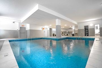 Montreal apartment for rent - A large indoor swimming pool with a blue tinted water.