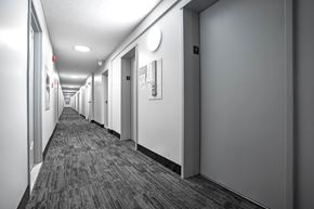 Montreal apartment for rent - A long hallway with doors on both sides and a carpeted floor.