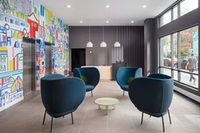 Philadelphia apartment for rent - A room with blue chairs and a wall with a mural of buildings.
