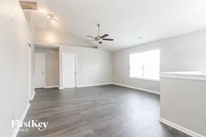Indianapolis house for rent - A spacious room with a ceiling fan and hardwood flooring.