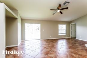 Lehigh Acres house for rent - an empty living room with a ceiling fan and tiled floors