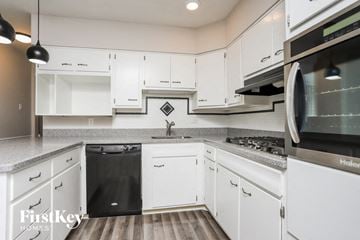 Saint Louis house for rent - a kitchen with white cabinets and stainless steel appliances
