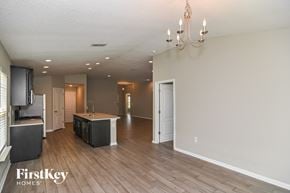 Fernandina Beach house for rent - A spacious living room with a kitchen area in the background and a chandelier hanging from the ceiling.