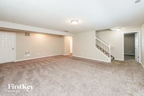 Coloradosprings house for rent - A spacious room with a carpeted floor and a staircase leading to another room.
