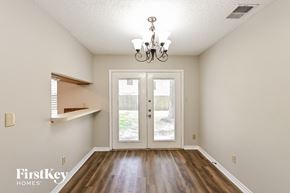 Spring house for rent - an empty dining room with a chandelier and doors to the backyard