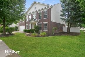 Fishers house for rent - A brick house with a white garage door and a tree in front.