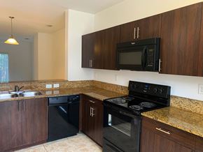 Boynton Beach apartment for rent - kitchen with blank appliances and dark wood cabinetry at Preserve at Boynton Beach, Boynton Beach, 33435
