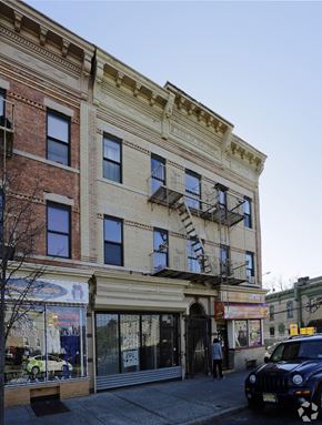 Jersey City apartment for rent - A building with a balcony and a car parked in front.