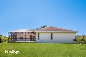 Lehigh Acres house for rent - a small white house with a greenhouse in a grass field