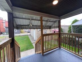 Glassport house for rent - A wooden deck with a white roof and a view of a green lawn and buildings.
