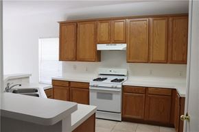 Cedar Park house for rent - an empty kitchen with white appliances and wooden cabinets