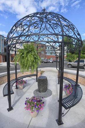 Abbeville apartment for rent - A black wrought iron gazebo with a cactus plant and purple flowers in front of a building.
