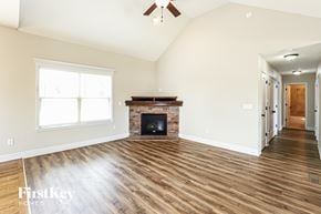 Basehor house for rent - A spacious living room with a fireplace and hardwood floors.