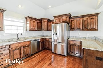 Basehor house for rent - A kitchen with wooden cabinets and a stainless steel refrigerator.