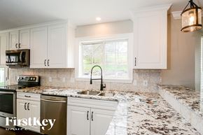 Arnold house for rent - a kitchen with marble counter tops and white cabinets