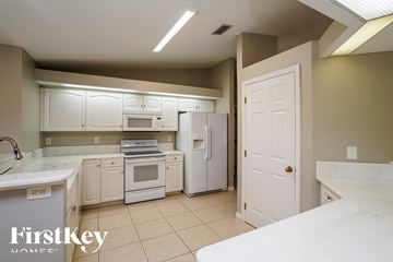 Cape Coral house for rent - a kitchen with white cabinets and appliances and a white refrigerator