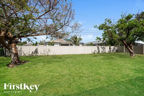 Cape Coral house for rent - a backyard with grass and trees and a white fence