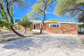 Tucson house for rent - a brick house with a driveway and trees