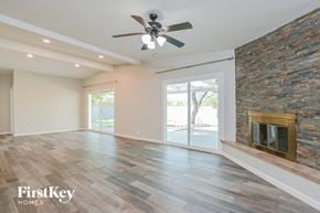 Tucson house for rent - an empty living room with a fireplace and a ceiling fan