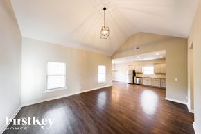 Parrish house for rent - A large empty room with wooden floors and a kitchen in the background.