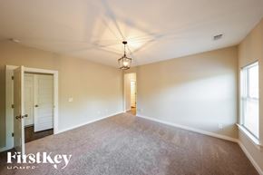 Parrish house for rent - A spacious room with a carpeted floor and a hanging light fixture.