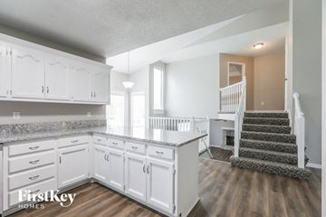 Lee's Summit house for rent - a white kitchen with white cabinets and a staircase