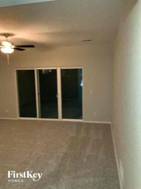 Colorado Springs house for rent - an empty living room with a ceiling fan and a window