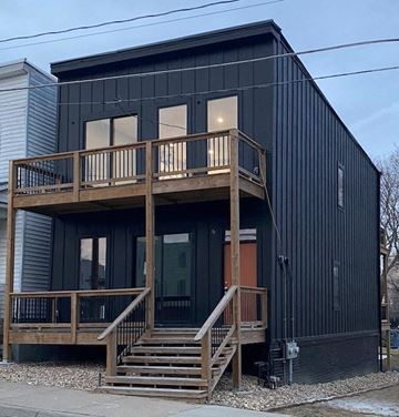 Omaha apartment for rent - A black house with a wooden deck and stairs.