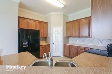 Midlothian house for rent - a kitchen with wooden cabinets and a sink and a refrigerator
