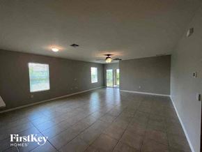 Cape Coral house for rent - an empty living room with a ceiling fan and a tiled floor