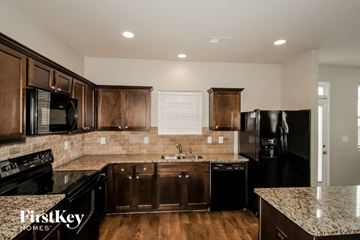 Hampton house for rent - A kitchen with wooden cabinets and black appliances.
