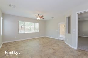 Marana house for rent - A spacious room with a ceiling fan and light fixture, and a doorway leading to another room.