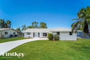 Rotonda West house for rent - a white house with a green lawn and palm trees
