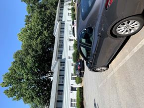 Greensboro apartment for rent - a car driving down a street next to a tall building