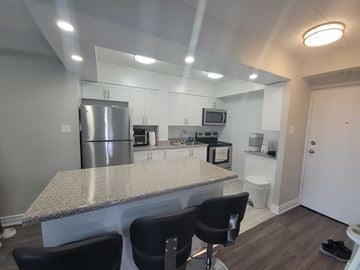 Oshawa apartment for rent - A kitchen with a granite countertop and black chairs.
